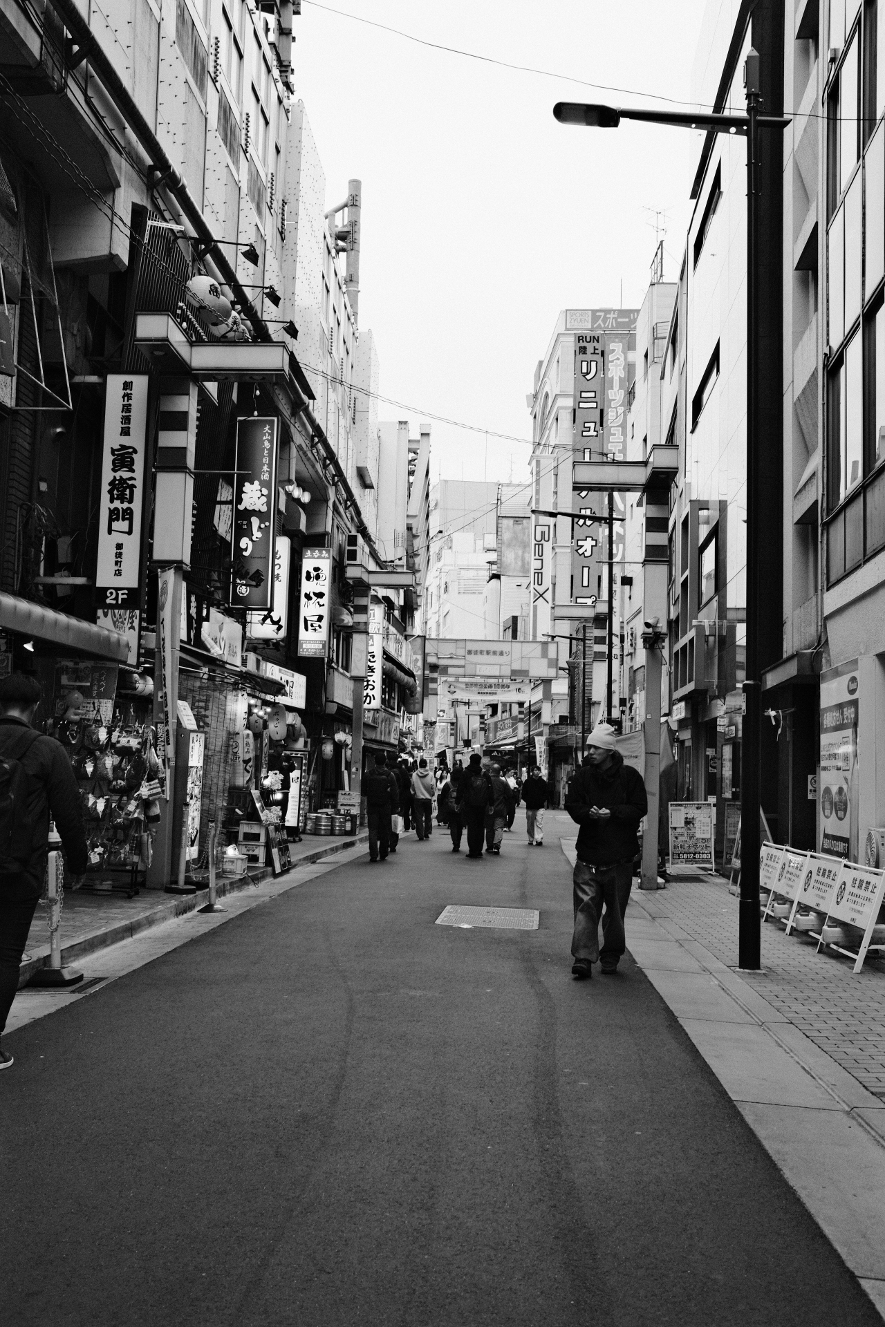Black and white Tokyo backstreet with a lone figure walking