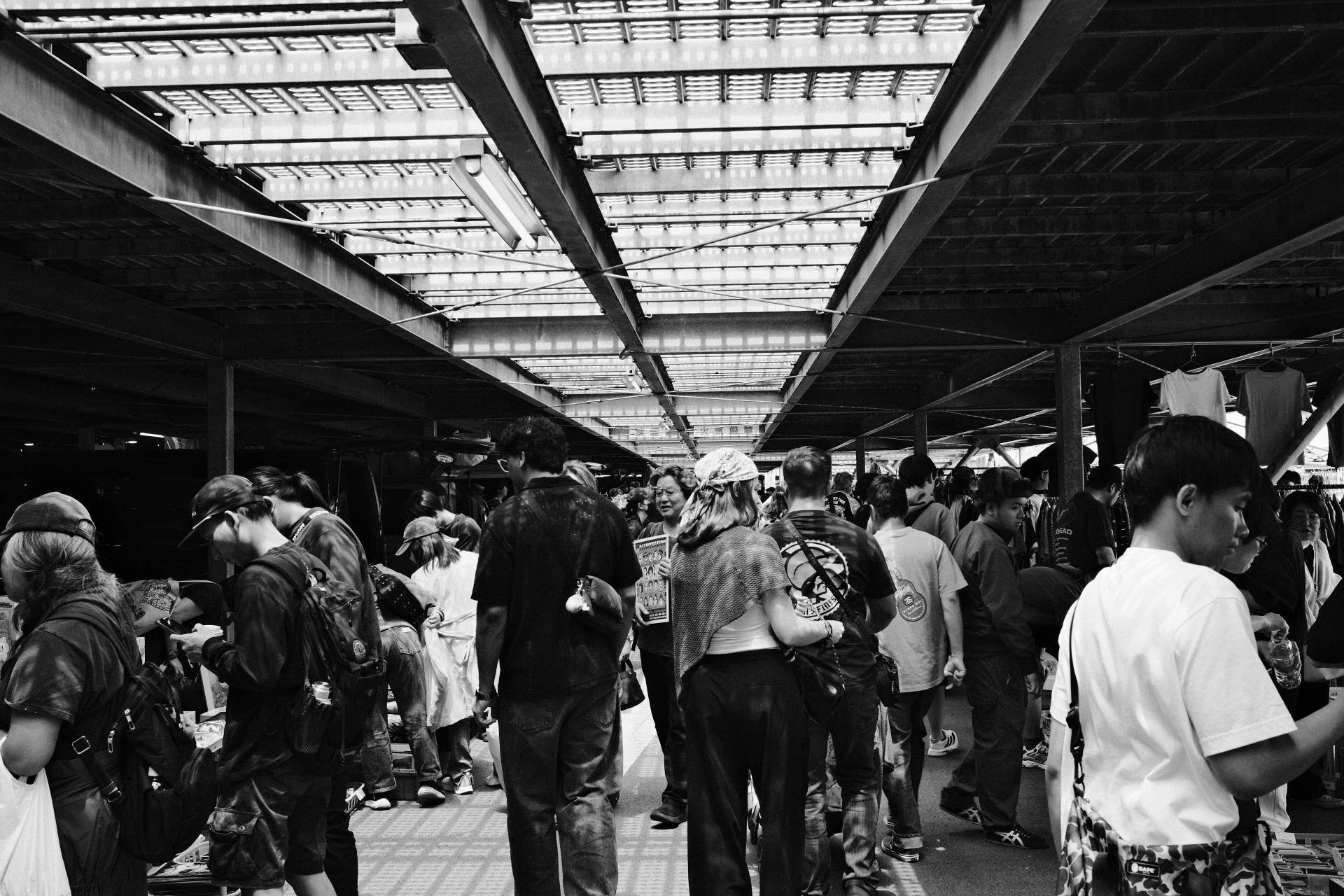 Crowd browsing a covered market beneath railway tracks