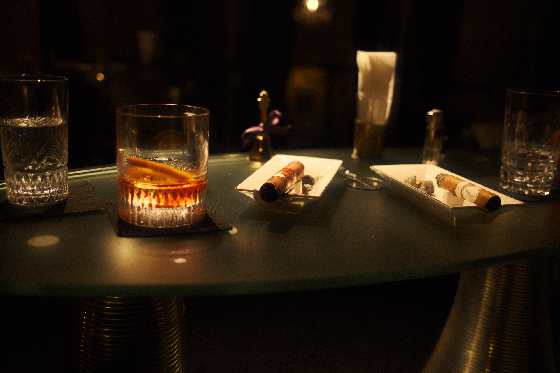 Whiskey glass and cigars on a low table in warm low light